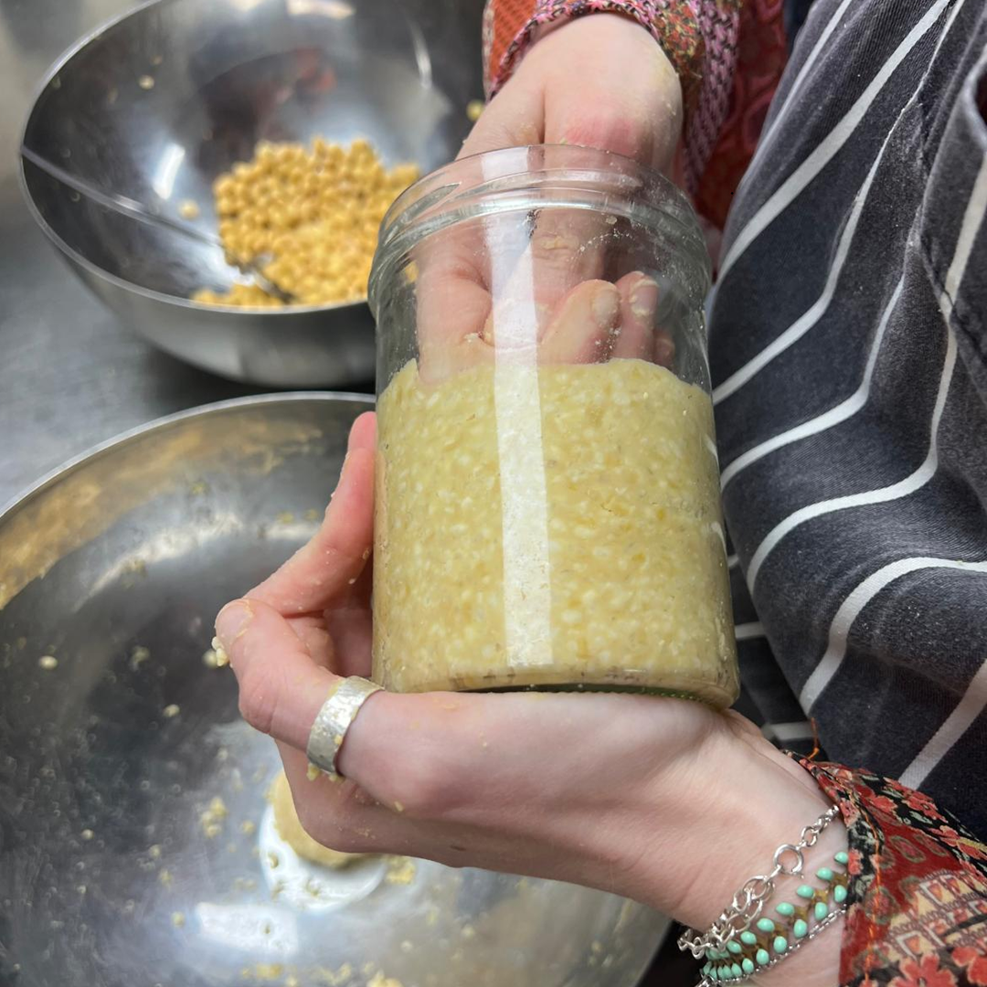 Miso being packed in glass jar by hand