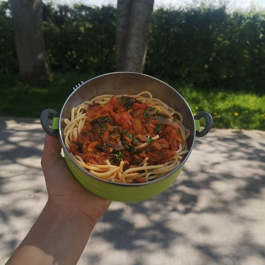 A green bowl filed with spagetti pasta and topped with a tomato sauce and kimchi