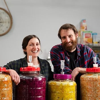 Team Crafty Pickles Madi and Arthur stood behind some vessels of sauerkraut