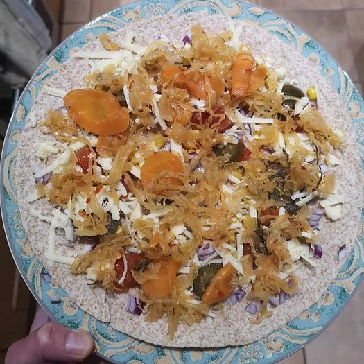 A plate with an open tortilla wrap covered in quesadilla filling and katz kimchi