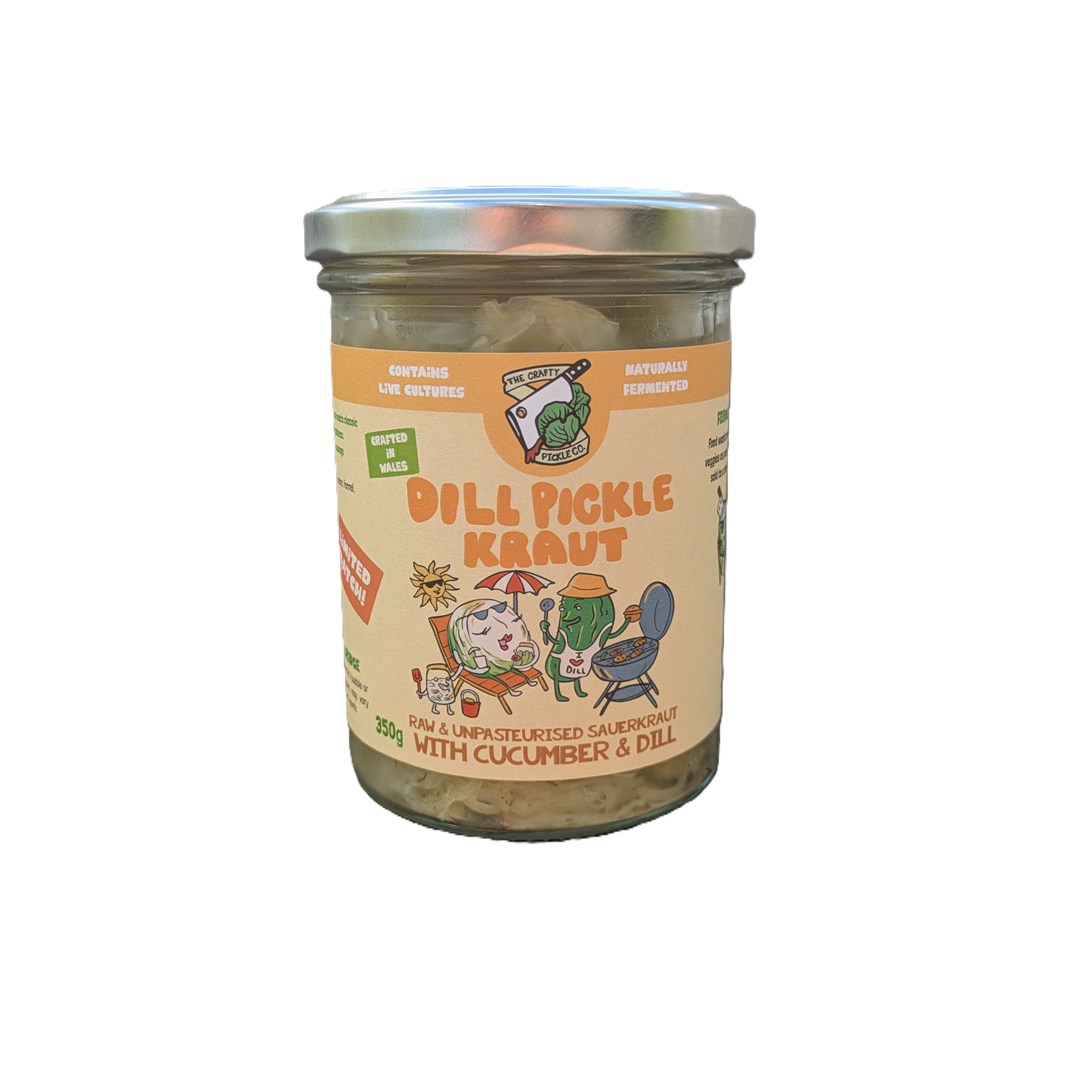 A glass jar of 'Dill Pickle Kraut' with a silver metal lid and a beige label featuring cartoon illustrations and orange text, set against a plain white background.