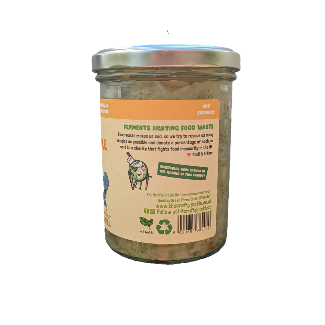 A glass jar of Dill Pickle Kraut, showing the back of the label with text and a cartoon illustration, topped with a silver metal lid.