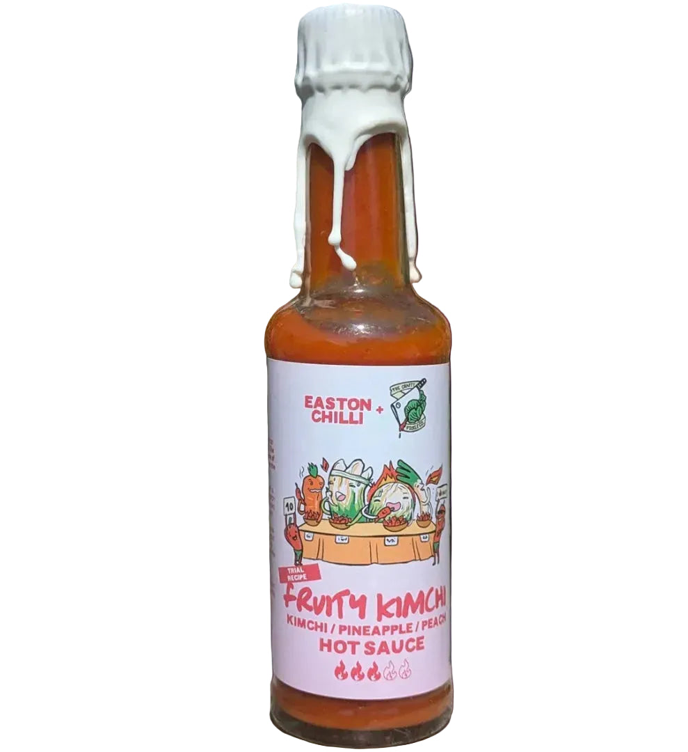 Bottle of fruity kimchi hot sauce in front of purple background