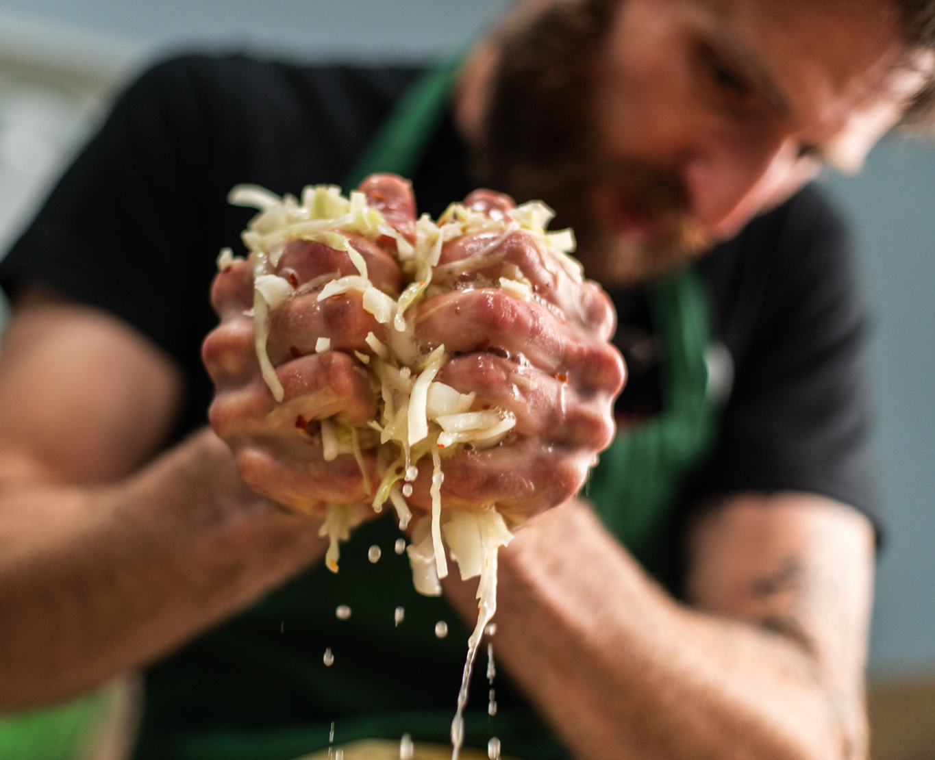 Hands squeezing liquid out of shredded cabbage